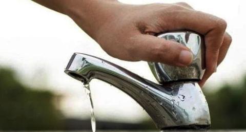 Mano che chiude un rubinetto dell'acqua aperto