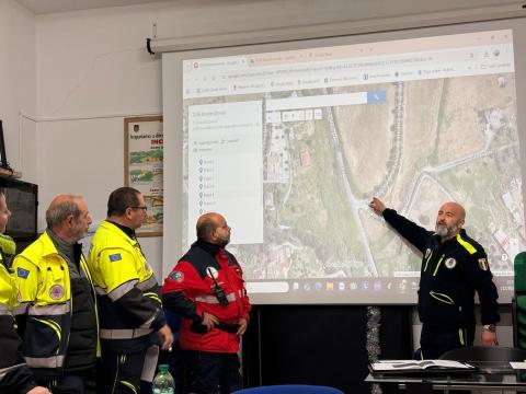 Foto con componenti protezione civile che illustrano su mappa cartografica